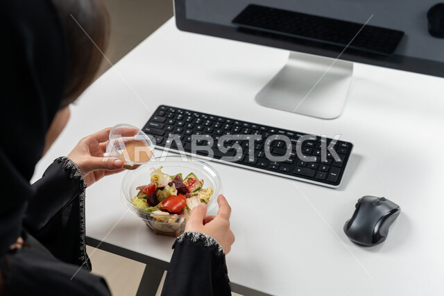 حمية غذائية لجسم رشيق ووزن مثالي , مقبلات باردة شهية, صورة مقربة لامراة عربية خليجية اماراتية محجبة ترتدي عباءة سوداء تجلس على كرسي مريح تقوم بتناول الطعام, وجبة صحية متكاملة مكونة من سلطة الخضروات الطازجة