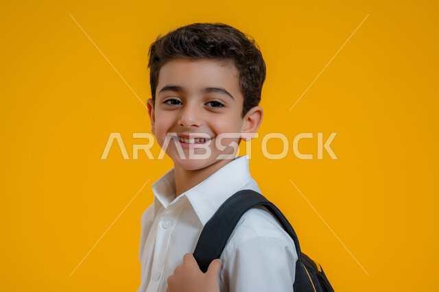 طالب مدرسي عربي خليجي سعودي يرتدي حقيبة ظهر مدرسية ، ارتداء الزي المدرسي التقليدي، ايماءات وجه تدل على السعادة ، امساك الحقيبة باليد ، خلفية صفراء 