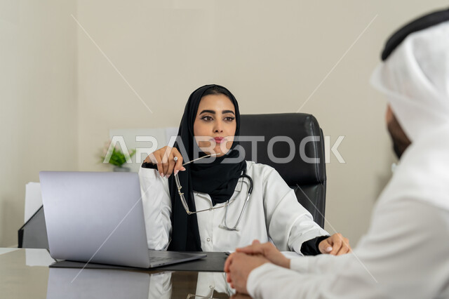 العمل في القطاعات الصحية, الاطلاع على نتائج التحاليل, تقديم الاستشارات في المراكز الطبيه في الامارات العربية المتحدة, متابعة السجل الطبي للمراجعين, بورتريه لطبيبة عربية خليجية اماراتية محجبة ترتدي المعطف الطبي تقوم بوصف الحالة المرضية للمريض, خلفية بيج