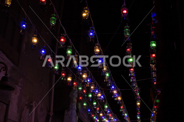 صورة لمجموعة من الفوانيس الملونة المضيئة المعلقة بشوارع جدة القديمة ليلا ، مدينة جدة القديمة ذات التصميم المعماري العربي والاسلامي القديم المزينة بأجواء رمضانية أماكن سياحية ، المملكة العربية السعودية