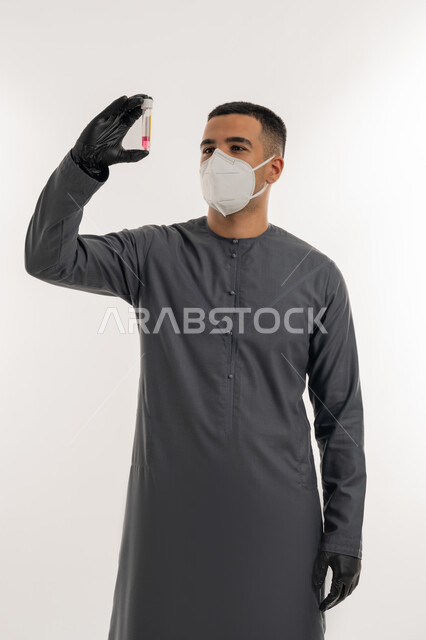 نشر الوعي الصحي للحد من انتشار الأمراض, اتباع الإجراءات الاحترازية للوقاية من فايروس كورونا، التطعيم الآمن لكوفيد19، بورتريه لطالب جامعي عربي خليجي إماراتي يرتدي الكندورة والكمامة يحمل بيده إبرة لقاح, خلفية رمادية