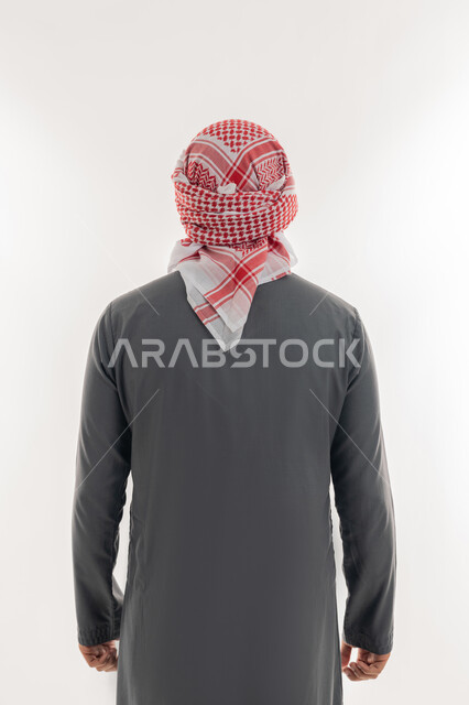 الاهتمام بالمظهر الخارجي, مفهوم الأناقة والرجولة, بورتريه من الخلف لشاب عربي خليجي إماراتي يرتدي الكندورة والعمامة يقف باستقامة واعتدال, خلفية بيضاء