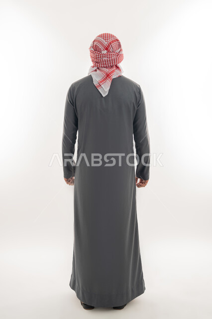 الاهتمام بالمظهر الخارجي, مفهوم الأناقة والرجولة, بورتريه من الخلف لشاب عربي خليجي إماراتي يرتدي الكندورة والعمامة يقف باستقامة واعتدال, الجسم بالطول الكامل, خلفية بيضاء