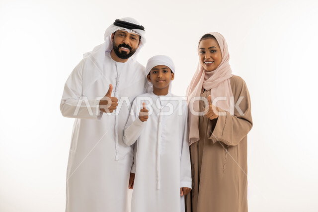 Success and achievement of goals, expressions of admiration and acceptance, family bonding and maintaining family stability, parents taking care of their children and caring for them, close-up portrait of an Emirati Arab family raising their thumbs up in approval and satisfaction, looking at the camera with gestures of happiness, white background