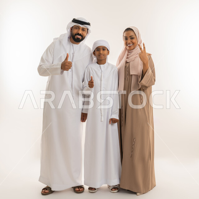 رعاية الآباء بأبنائهم والاهتمام بهم، تعابير الإعجاب والقبول، الترابط الأسري والحفاظ على الاستقرار العائلي، بورتريه لعائلة عربية اماراتية يرفعون اصبع الابهام للأعلى بهدف الرضا والموافقة، النظر للكاميرا بإيماءات السعادة، صورة الجسم بالطول الكامل، خلفية بيضاء