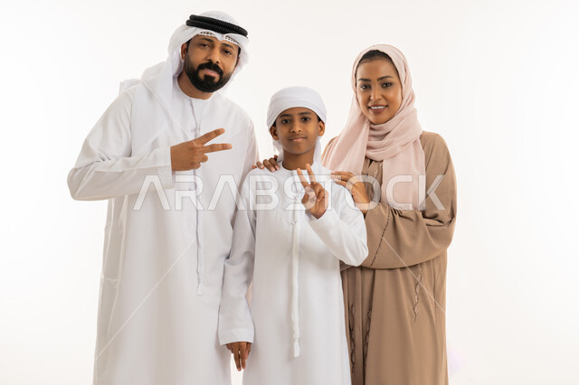 تعابير السعادة بالوصول الى الغايات، النجاح وتحقيق الأهداف، مفهوم الفوز والانتصار، الألفة والمحبة بين أفراد الأسرة، بورتريه مقرب لعائلة عربية خليجية اماراتية يرفعون ايديهم بإشارة النصر والقوة، النظر الى الكاميرا بإيماءات الثقة بالنفس، خلفية بيضاء