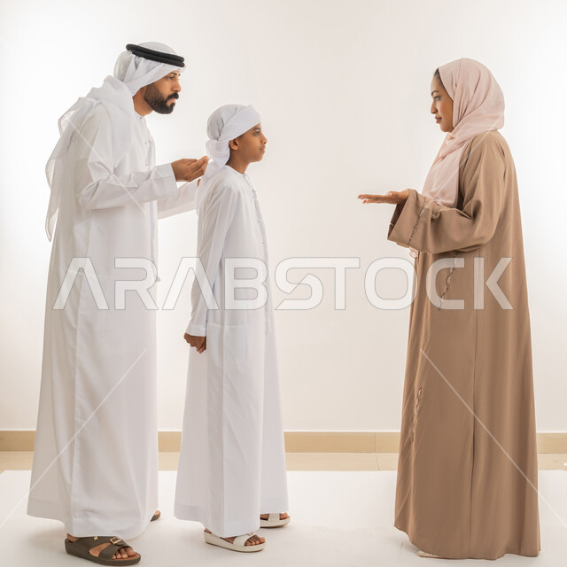 Discussions and dialogues between family members, intimacy, love and family cohesion, maintaining family stability, parents taking care of their children and caring for them, portrait of an Arab Gulf Emirati family exchanging news and conversations, full-length body image, white background