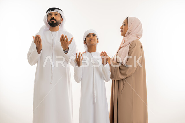 إيماءات التوسل والاسترحام، طلب المساعدة من المولى عز وجل، الحمد والشكر والتضرع  لله تعالى، بورتريه مقرب لعائلة عربية خليجية اماراتية ويقوموا برفع أيديهم للأعلى بهدف الدعاء بإيماءات السعادة والرضا، خلفية بيضاء