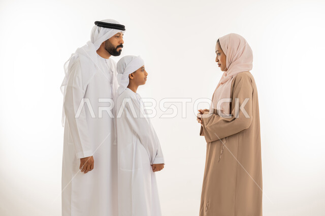 ايماءات التوبيخ والتنبيه، الوقوف بجدية والأمر بالتوقف عن فعل شيء ما، بورتريه مقرب لإمرأة عربية خليجية اماراتية ترتدي الحجاب والعباءة تقف برفقة زوجها وابنها وتنظر الى ولدها بهدف التهديد والتوعد والنهي عن أمر معين، خلفية بيضاء