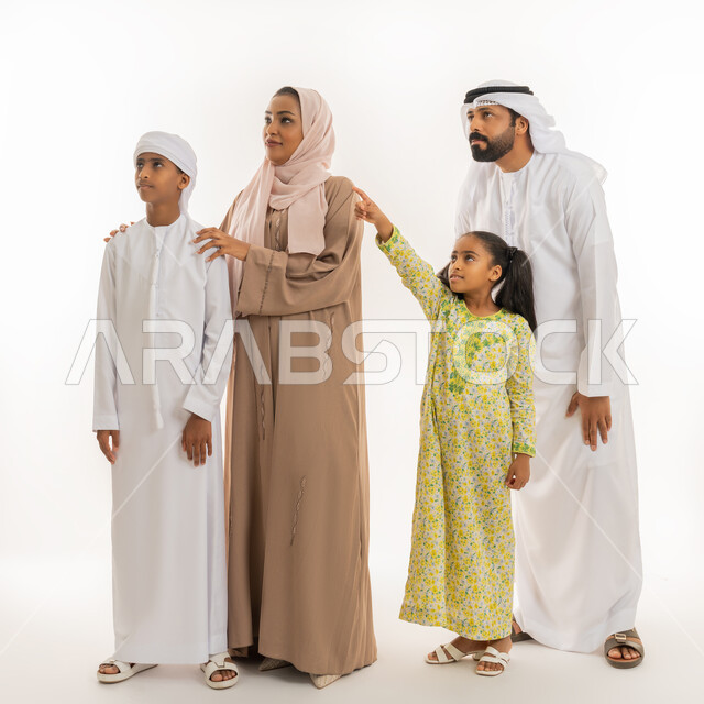 التوجه والإشارة الى شيء ما، النظر الى مكان معين، مفهوم لغة الجسد، بورتريه لفتاة عربية خليجية اماراتية ترتدي لباس الكاجوال تقف برفقة عائلتها  وتشير بإصبع السبابة الى الأعلى دلالة على موقع محدد، صورة الجسم بالطول الكامل، خلفية بيضاء