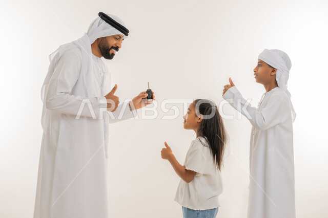 غغغالحصول على رخصة القيادة، ايماءات السعادة والسرور، إقتناء سيارة جديدة، بورتريه مقرب من الجانب لرجل عربي خليجي اماراتي يرتدي الكندورة والغترة يحمل بيده جهاز التحكم الالكتروني يقوم بمفاجأة ابنائه ويرفعون اصبع الابهام للأعلى بتعابير الاعجاب والرضا، خلفية بيضاء