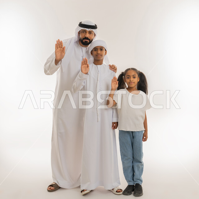 الوقوف بانزعاج ورفض أمر محدد، الامتناع عن فعل شيء معين، بورتريه لرجل عربي خليجي اماراتي يرتدي الكندورة والغترة يقف برفقة أبنائه ويشيروا بأيديهم الى الأعلى بتعابير عدم التدخل، النظر الى الكاميرا بإيماءات النهي والصمت، صورة الجسم بالطول الكامل، خلفية بيضاء