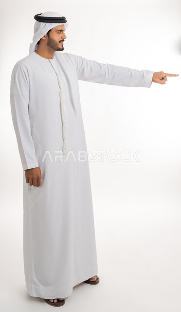 Pointing and explaining something, specifying a specific location, indicating the location of an item, portrait of an Arab Gulf Emirati man wearing a white kandura and ghutra pointing with his index finger to something, full body, white background