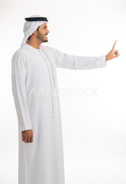 Pointing and explaining something, specifying a specific location, indicating the location of an item, portrait of an Arab Gulf Emirati man wearing a white kandura and ghutra pointing with his index finger to something, full body, white background
