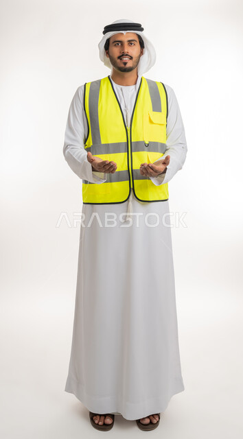 Concept of engineering and architectural construction, expressions of presentation and display, working in the engineering sector, portrait of an Arab Gulf Emirati engineer wearing a white kandura and ghutra with a protective jacket, opening his hands up with gestures of carrying an item, white background