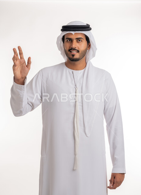 The concept of reception and welcome, greeting and peace, portrait of an Arab Gulf Emirati man wearing a white kandura and ghutra, looking and extending his hand with handshake gestures, acquaintance, friendship and building relationships, white background