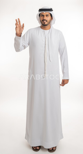 The concept of reception and welcome, greeting and peace, portrait of an Arab Gulf Emirati man wearing a white kandura and ghutra, looking and extending his hand with handshake gestures, acquaintance, friendship and building relationships, white background