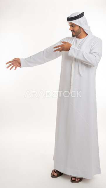 القلق والاحتياط والابتعاد عن شيء ما, حماية النفس من ضرر خارجي, بورتريه لرجل  عربي خليجي اماراتي يرتدي الكندورة والغترة البيضاء يرفع يديه للاعلى بإيماءات التوقف وعدم الاقتراب، مفهوم الحذر وترك مسافة، خلفية بيضاء