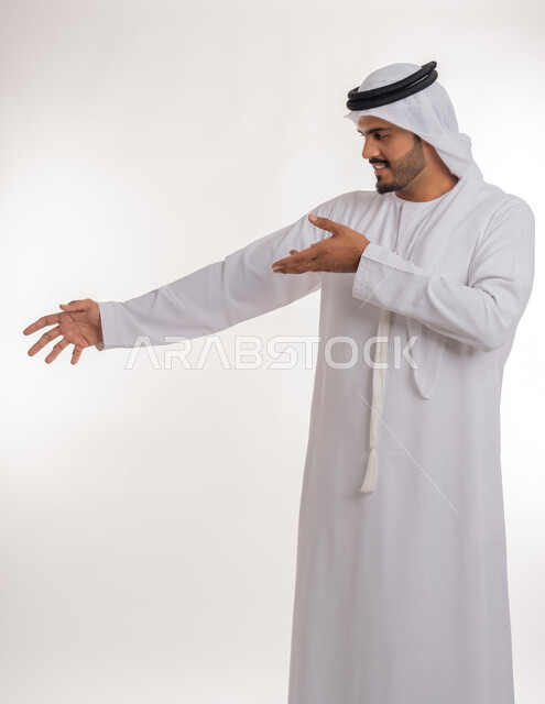 القلق والاحتياط والابتعاد عن شيء ما, حماية النفس من ضرر خارجي, بورتريه لرجل  عربي خليجي اماراتي يرتدي الكندورة والغترة البيضاء يرفع يديه للاعلى بإيماءات التوقف وعدم الاقتراب، مفهوم الحذر وترك مسافة، خلفية بيضاء