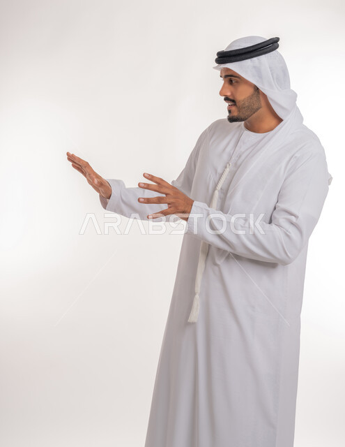 القلق والاحتياط والابتعاد عن شيء ما, حماية النفس من ضرر خارجي, بورتريه لرجل  عربي خليجي اماراتي يرتدي الكندورة والغترة البيضاء يرفع يديه للاعلى بإيماءات التوقف وعدم الاقتراب، مفهوم الحذر وترك مسافة، خلفية بيضاء