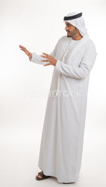 القلق والاحتياط والابتعاد عن شيء ما, حماية النفس من ضرر خارجي, بورتريه لرجل  عربي خليجي اماراتي يرتدي الكندورة والغترة البيضاء يرفع يديه للاعلى بإيماءات التوقف وعدم الاقتراب، مفهوم الحذر وترك مسافة، خلفية بيضاء