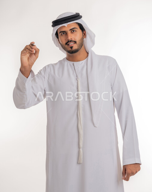 Using pens to mark objects and important points, preparing to write something on air, portrait of an Arab Gulf Emirati man wearing a white kandura using a pen to write down notes and ideas, white background