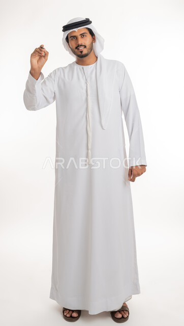 Using pens to mark objects and important points, preparing to write something on air, portrait of an Arab Gulf Emirati man wearing a white kandura using a pen to write down notes and ideas, white background