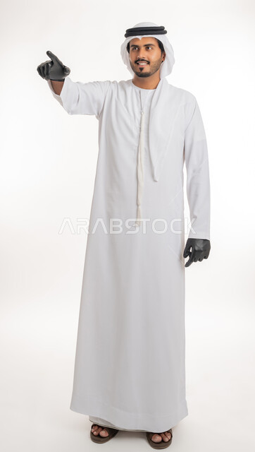 اشارات تحدد هذا المكان (هنا)، الاشارة إلى شيء ما، تعابير التحديد والتأكيد, بورتريه لرجل عربي خليجي اماراتي يرتدي الكندورة والغترة البيضاء مع قفازات الوقاية يقف باستقامة و يشير بأصابع السبابة للاختيار، خلفية بيضاء