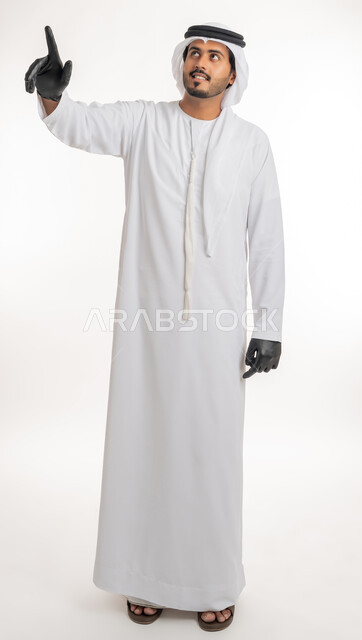 اشارات تحدد هذا المكان (هنا)، الاشارة إلى شيء ما، تعابير التحديد والتأكيد, بورتريه لرجل عربي خليجي اماراتي يرتدي الكندورة والغترة البيضاء مع قفازات الوقاية يقف باستقامة و يشير بأصابع السبابة للاختيار، خلفية بيضاء