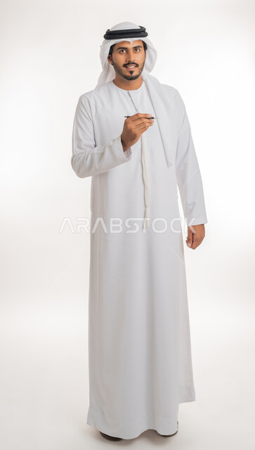 Using pens to mark objects and important points, preparing to write something on air, portrait of an Arab Gulf Emirati man wearing a white kandura using a pen to write down notes and ideas, white background