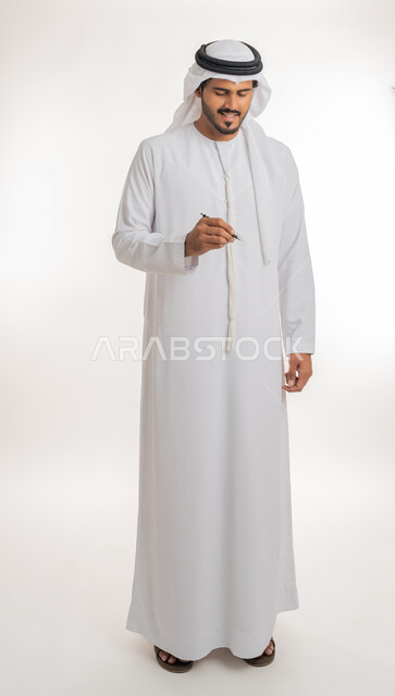 استخدام الأقلام  لتحديد الأشياء و النقاط المهمة، الإستعداد لكتابة شيء ما على الهواء، بورتريه لرجل عربي خليجي اماراتي يرتدي الكندورة البيضاء يستخدم القلم لتدوين الملاحظات والأفكار، خلفية بيضاء