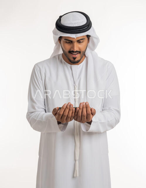الإكثار من الدعاء في شهر رمضان المبارك، الإجتهاد في العبادة والحفاظ على الطاعات، بورتريه لرجل عربي خليجي اماراتي يرتدي الكندورة والغترة البيضاء يرفع يديه ويدعو الله بإيماءات التوسل والتضرع، خلفية بيضاء