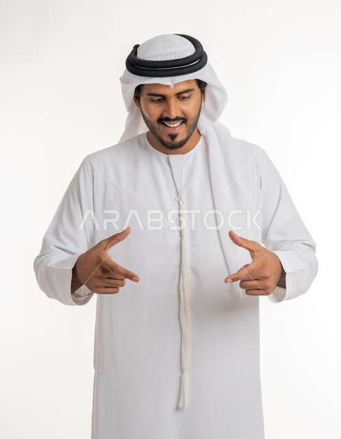 استخدام اليدين لتحجيم شيء ما، تحديد الحجم والكتلة، بورتريه لرجل عربي خليجي اماراتي يرتدي الكندورة البيضاء يقوم برفع يديه بإيماءات حمل عنصر معين، خلفية بيضاء