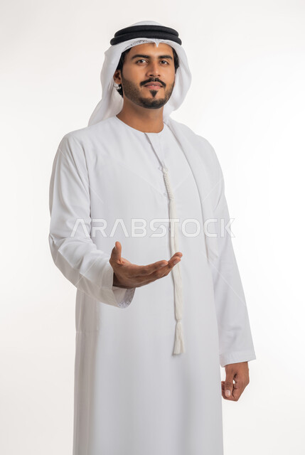 تحديد الحجم والكتلة، استخدام اليدين لتحجيم شيء ما، بورتريه لرجل عربي خليجي اماراتي يرتدي الكندورة البيضاء يقوم برفع يده بإيماءات حمل عنصر معين، خلفية بيضاء
