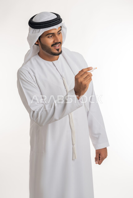 الإستعداد لكتابة شيء ما على الهواء، استخدام أقلام الهايلايتر لتحديد الأشياء و النقاط المهمة، بورتريه لرجل عربي خليجي اماراتي يرتدي الكندورة البيضاء يستخدم القلم لتدوين الملاحظات والأفكار، خلفية بيضاء