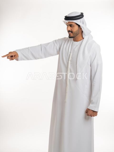 الدلالة على مكان عنصر،  الإشارة و التوضيح إلى شيء ما, تحديد موقع معين، بورتريه لرجل عربي خليجي إماراتي يرتدي الكندورة و الغترة البيض يشير بإصبع السبابة إلى شيء ما، خلفية بيضاء