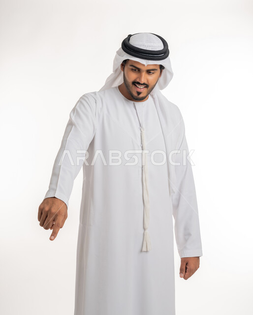 الدلالة على مكان عنصر،  الإشارة و التوضيح إلى شيء ما, تحديد موقع معين، بورتريه لرجل عربي خليجي إماراتي يرتدي الكندورة و الغترة البيض يشير بإصبع السبابة إلى شيء ما، خلفية بيضاء