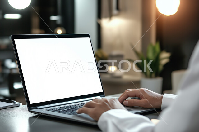 تصفح الانترنت وبرامج التواصل الاجتماعي، إنجاز العمل اونلاين من خلال الحاسب المحمول، صورة مقربة لرجل عربي خليجي سعودي يرتدي الزي التقليدي و يقوم بالعمل على الحاسب المحمول، تطور التكنولوجيا وإستخدام الأجهزة التقنية الحديثة