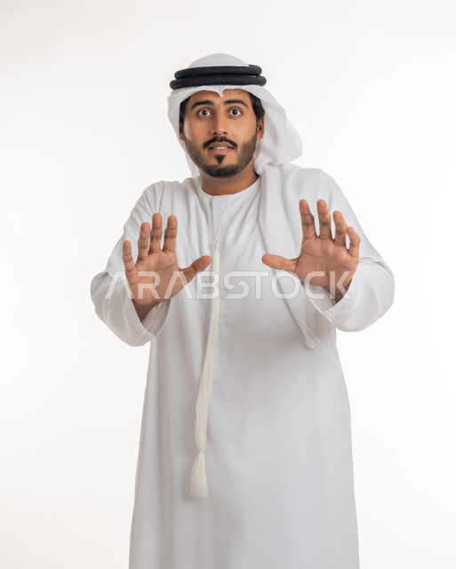 حماية النفس من ضرر خارجي, طلب التوقف و الامتناع و عدم الاقتراب, بورتريه مقرب لرجل عربي خليجي إماراتي يرتدي الكندورة والغترة ينظر إلى الكاميرا و يرفع يديه بتعابير الخوف و الابتعاد,  خلفية بيضاء