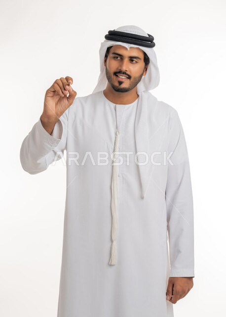 Hand gestures indicating holding an item, preparing to write and specifying something, close-up portrait of an Arab, Gulf, Emirati teacher wearing a kandora and ghutra, holding a pen in his hand, the concept of education according to the prescribed curricula, white background.