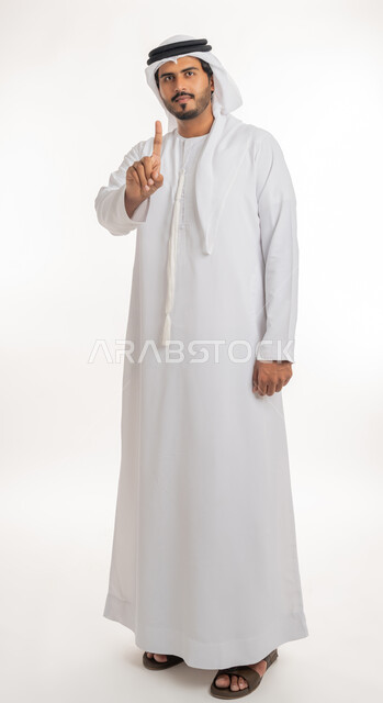 الإشارة و التوضيح إلى شيء ما, تحديد موقع معين, الدلالة على مكان عنصر، بورتريه لرجل عربي خليجي إماراتي يرتدي الكندورة و الغترة البيض يشير بإصبع السبابة إلى شيء ما، الجسم بالطول الكامل، خلفية بيضاء