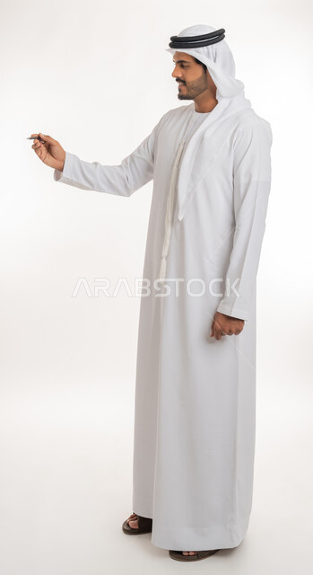 الإستعداد للكتابة وتحديد شيء ما, إيماءات يدين تدل على الإمساك بعنصر ما, بورتريه لمعلم عربي خليجي امارتي يرتدي الكندورة و الغترة يمسك بيده قلم, مفهوم التعليم بالمناهج المقررة، صورة الجسم بالطول الكامل, خلفية بيضاء
