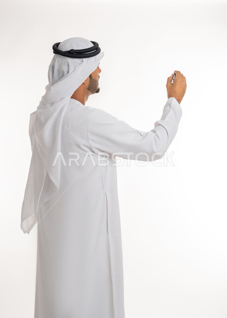 إيماءات يدين تدل على الإمساك بعنصر ما, الإستعداد للكتابة وتحديد شيء ما, بورتريه مقرب من الخلف لمعلم عربي خليجي امارتي يرتدي الكندورة و الغترة يمسك بيده قلم, مفهوم التعليم بالمناهج المقررة، خلفية بيضاء
