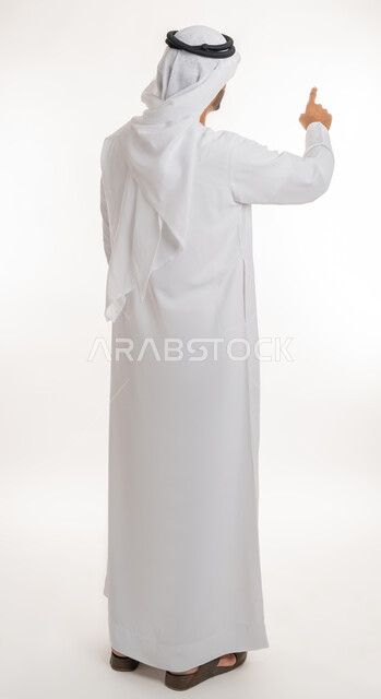 تحديد موقع معين، بورتريه من الخلف لرجل عربي خليجي اماراتي يرتدي الكندورة والغترة البيضاء يرفع يده للاعلى يشير بأصبع السبابة الى هدف محدد، الجسم بالطول الكامل، خلفية بيضاء