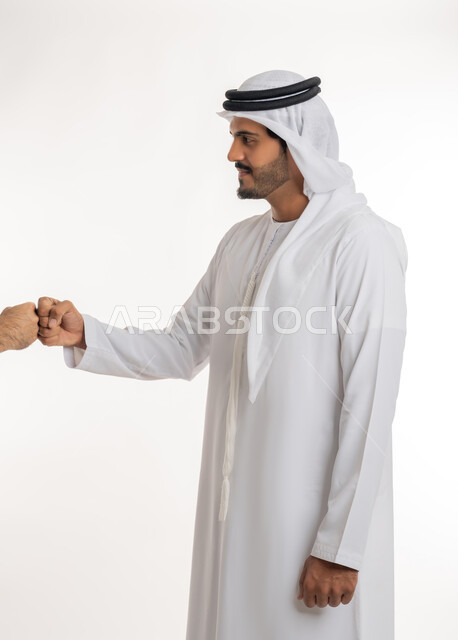 The concept of reception and welcome, greeting and peace, close-up portrait of an Arab Gulf Emirati man wearing a white kandura and ghutra looking at and extending his hand with handshake gestures, acquaintance, friendship and building relationships, white background