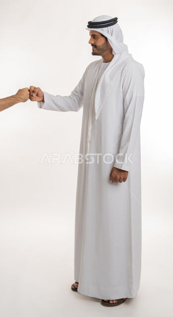 التعارف و الصداقه وتكوين العلاقات، مفهوم الاستقبال والترحيب، إلقاء التحيه والسلام، بورتريه لرجل عربي خليجي إماراتي يرتدي الكندورة والغترة  يمد يده بإيماءات المصافحة، صورة الجسم بالطول الكامل, خلفية بيضاء
