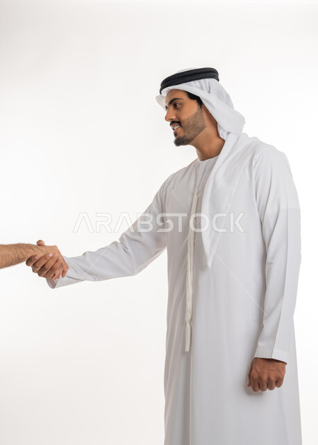 مفهوم الاستقبال والترحيب، إلقاء التحيه والسلام، بورتريه مقرب لرجل عربي خليجي إماراتي  يرتدي الكندورة والغترة البيضاء ينظر يمد يده بإيماءات المصافحة، التعارف و الصداقه وتكوين العلاقات، خلفية بيضاء