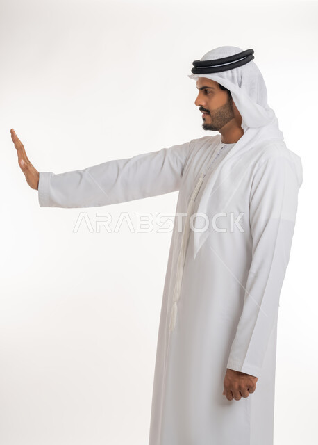 النهي عن فعل أمر ما، مفهوم الرفض والامتناع والانزعاج، بورتريه من الجانب لرجل عربي خليجي إماراتي يرتدي الكندورة والغترة يرفع يده بإيماءات التوقف وعدم الاقتراب، خلفية بيضاء