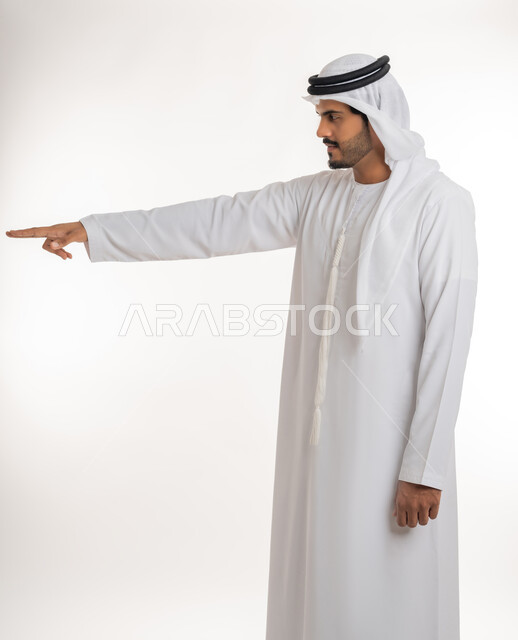 الدلالة على مكان عنصر،  الإشارة و التوضيح إلى شيء ما, تحديد موقع معين، بورتريه لرجل عربي خليجي إماراتي يرتدي الكندورة و الغترة البيض يشير بإصبع السبابة إلى شيء ما، خلفية بيضاء