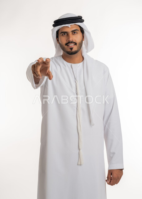 مفهوم الاناقة و الاهتمام بالمظهر الخارجي, إحتواء وإمساك عنصر ما، بورتريه مقرب لرجل عربي خليجي اماراتي يرتدي الكندورة و العمامة يعرض عنصر هولوجرامي ثلاثي الأبعاد،  خلفية بيضاء